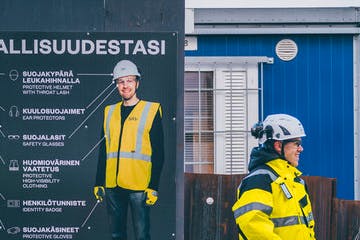 Työntekijät juttelevat työmaan portilla.