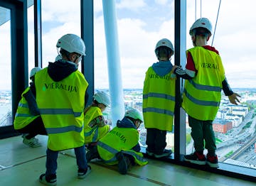 Lapset korkeassa tornitalossa ikkunan ääressä huomioliiveissä