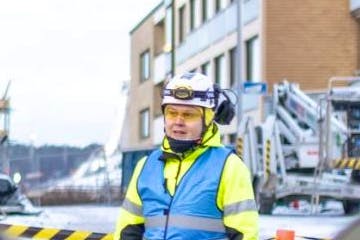 Lapsia rakennustyömaan vieressä, aikuisia ohjeistamassa