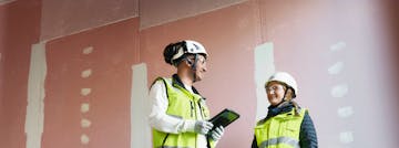 Nainen ja mies keskustelemassa työmaalla